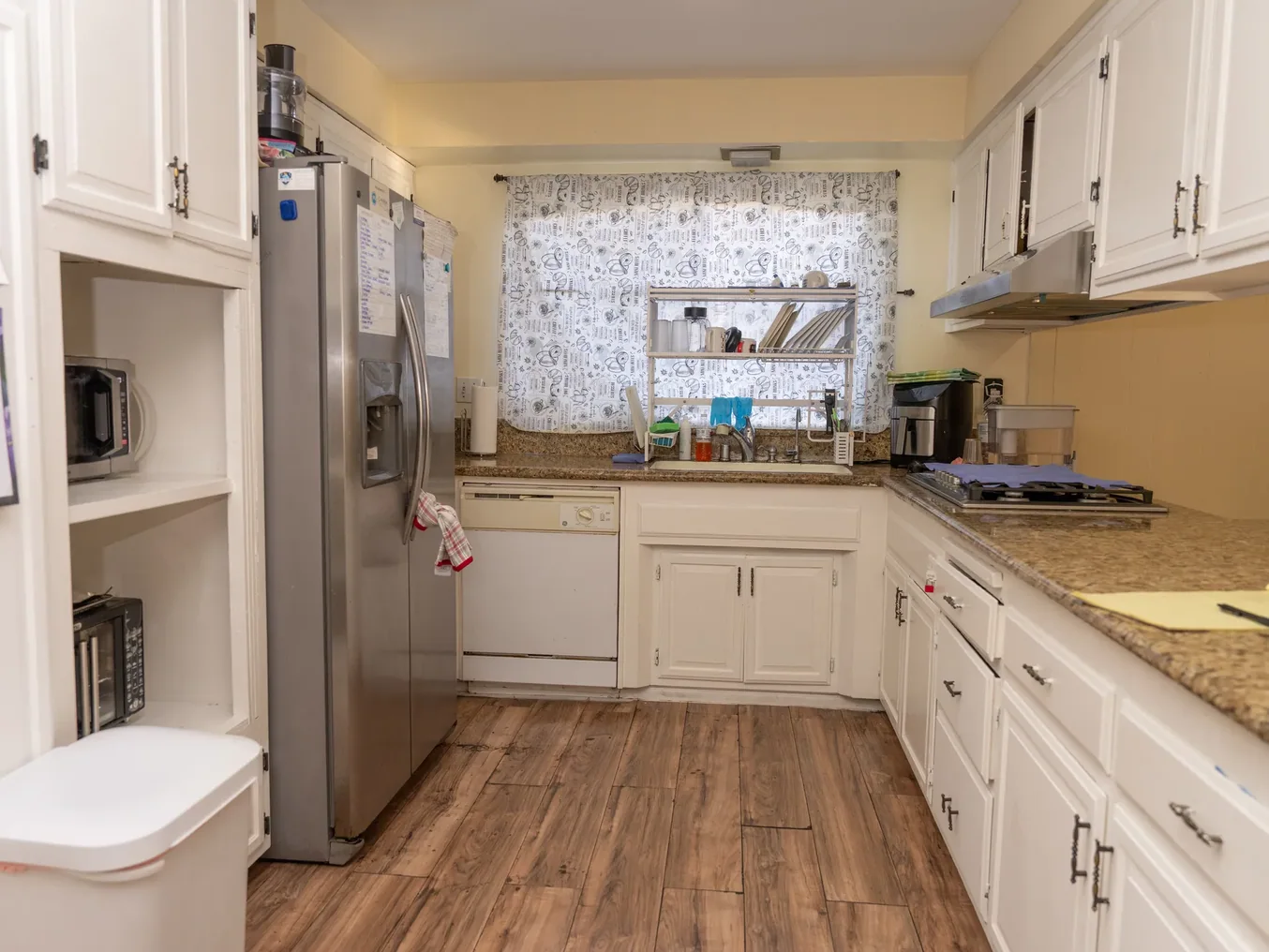 Spacious residential care facility kitchen with white cabinetry, granite counters, and modern appliances