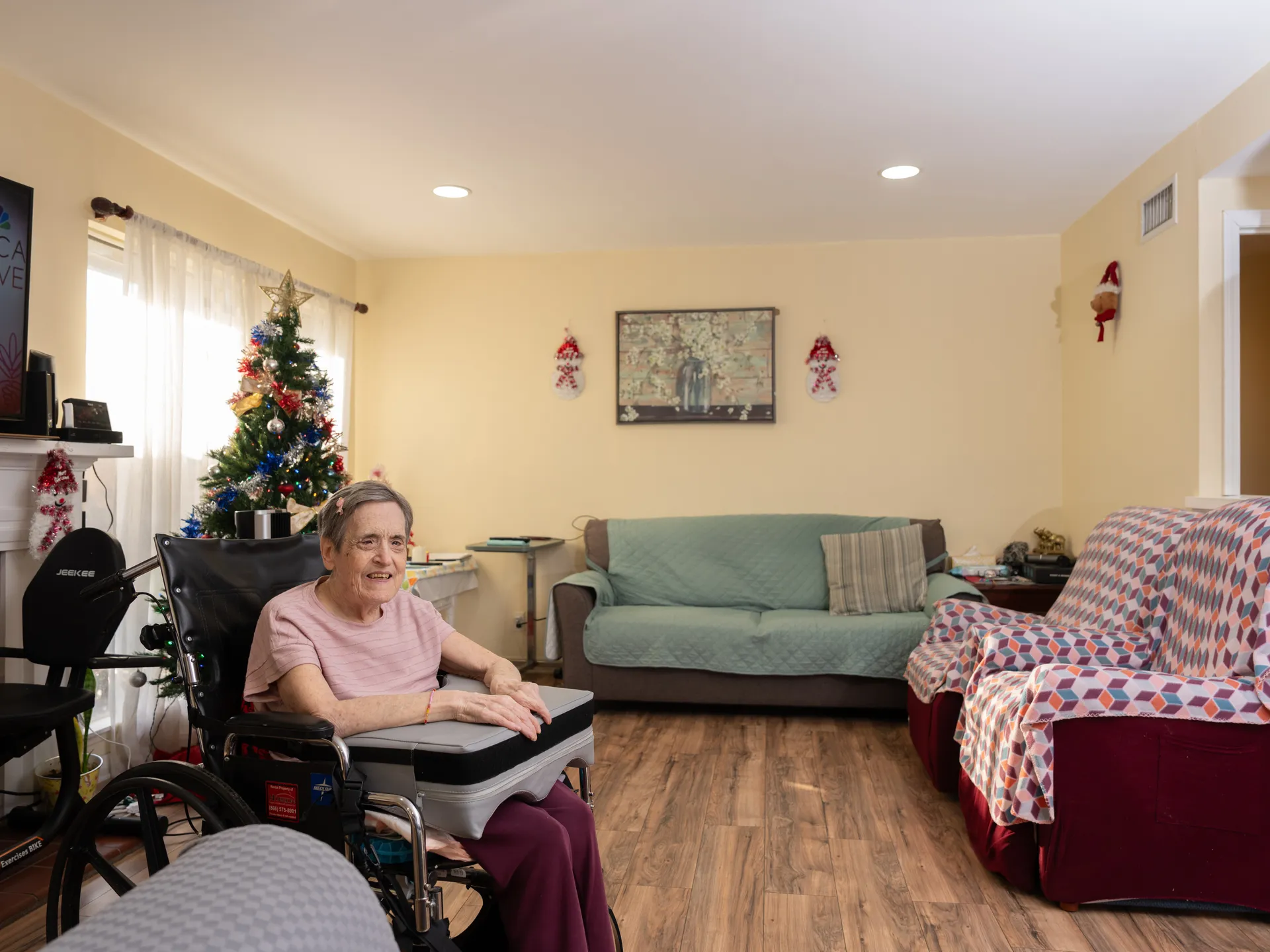 Smiling senior resident in wheelchair in comfortable living room with holiday decorations