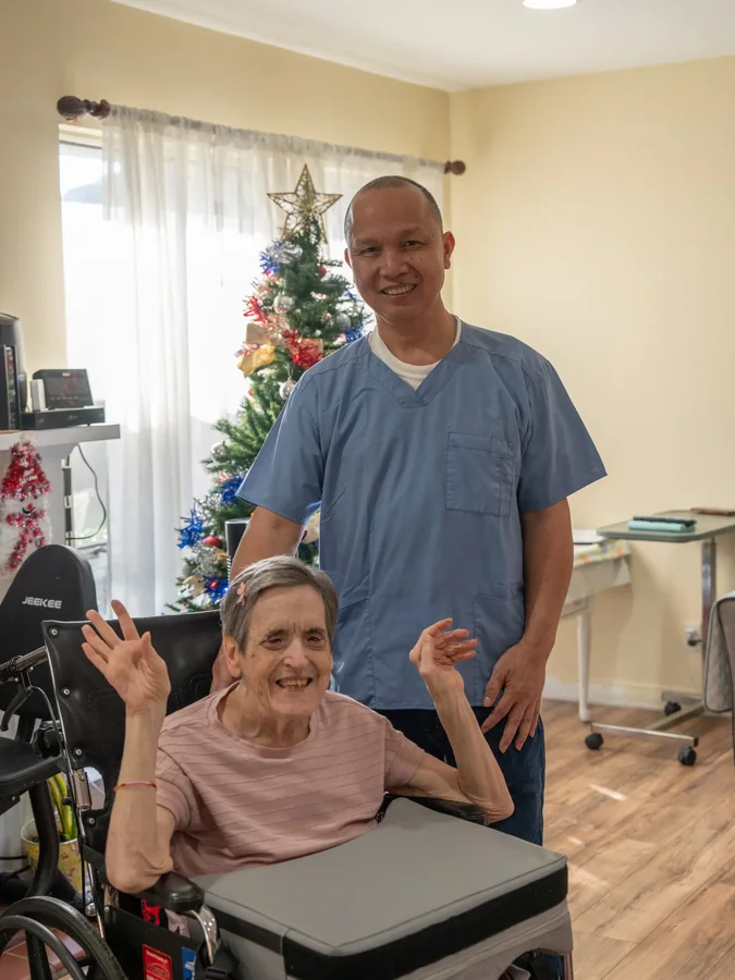 Smiling caregiver and resident celebrating the holidays together in comfortable care home setting